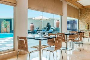 a dining room with tables and chairs and a large window at Le Meridien Fairway in Dubai