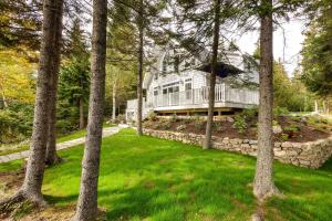 Una gran casa blanca en el bosque con árboles. en Oceanfront Prospect Harbor House with Deck, View, en Prospect Harbor