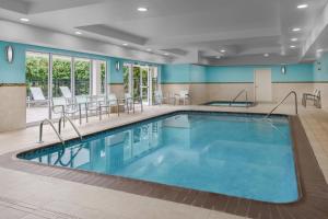 uma piscina num quarto de hotel com cadeiras e mesas em SpringHill Suites Providence West Warwick em West Warwick
