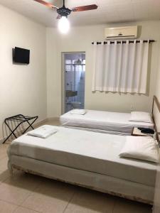 two beds in a room with a window and a tv at Regio Plaza Hotel in Ourinhos