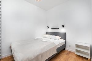 ein Schlafzimmer mit weißen Wänden und ein Bett mit weißer Bettwäsche in der Unterkunft Solidarności 68 by Homeprime in Warschau