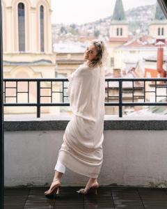 a woman in a white dress standing on a balcony at Sarajevo Skyline Apartment in Sarajevo