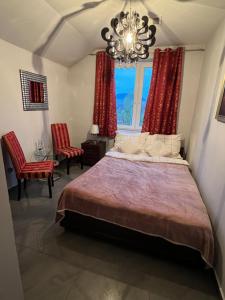 a bedroom with a bed with red curtains and a chandelier at Apartamenty Południe BB in Bielsko-Biała