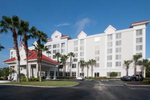 a large white building with palm trees in front of it at SpringHill Suites by Marriott Orlando Lake Buena Vista South in Kissimmee