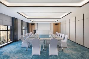 uma sala de conferências com uma mesa longa e cadeiras brancas em Fairfield by Marriott Hangzhou Xihu District em Hangzhou