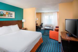 a hotel room with a bed and a flat screen tv at Fairfield Inn & Suites Chicago Tinley Park in Tinley Park