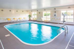 una piscina en una habitación de hotel con sillas y mesa en Fairfield Inn & Suites Chicago Tinley Park, en Tinley Park