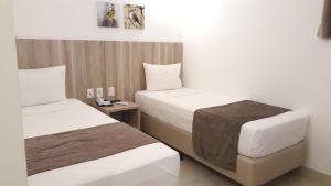 a hotel room with two beds and a table at Pena Branca Hotel e Eventos in Santo Antônio de Jesus