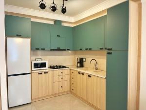 庫塔伊西的住宿－City Heart Luxury Apartment，厨房配有绿色橱柜和白色冰箱