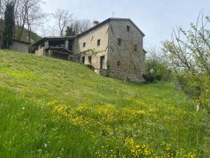 un vieux bâtiment sur une colline avec un champ de fleurs dans l'établissement Gamberotti private valley, à Santa Sofia