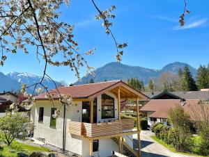 a house with a deck with mountains in the background at Fuxbau Waldlounge inklusive Chiemgaukarte in Ruhpolding