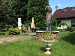 a garden with a fountain and an umbrella in a yard at Tolles Appartement in Gehren mit Garten, Terrasse und Grill in Heideblick
