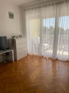 a living room with a wooden floor and a large window at Apartments Vip in Split