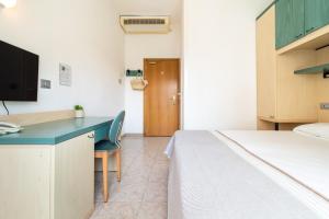 a bedroom with a bed and a desk with a computer at Hotel Ettoral in Lido di Jesolo