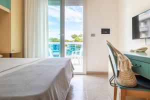 1 dormitorio con cama y vistas a un balcón en Hotel Ettoral en Lido di Jesolo