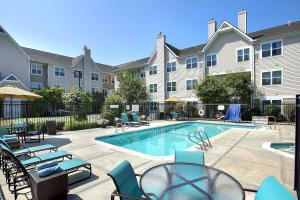 a swimming pool with chairs and tables and a building at Residence Inn Boston Andover in Andover