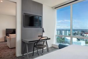 een slaapkamer met een bureau, een tv en een raam bij Four Points by Sheraton Auckland in Auckland