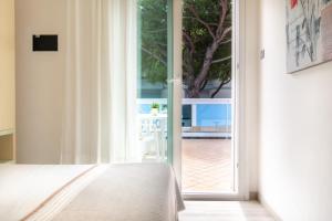 una camera con letto e porta scorrevole in vetro di Hotel Ettoral a Lido di Jesolo