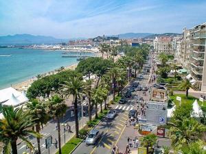 a busy city street with palm trees and the ocean at The Beach Dream in Saint-Laurent-du-Var