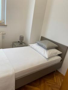 a bed with white sheets and a pillow on it at Apartments Vip in Split
