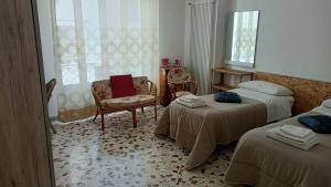 a room with two beds and a chair and a window at Dimora Nonna Dora in Polignano a Mare