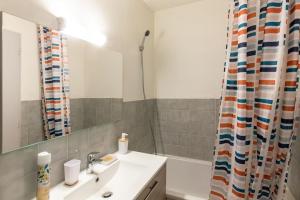 a bathroom with a sink and a shower curtain at Elégant studio, proche de la place Wilson in Dijon