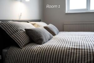 a bed with striped sheets and pillows in a bedroom at Town House Chantry - With Self Check In and Free Parking - Rooms at ipswichdigs in Ipswich
