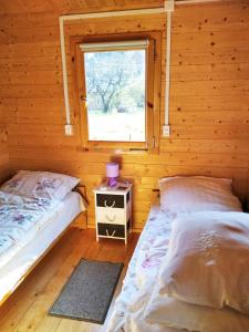 2 camas en una cabaña de madera con ventana en Domek nad Olszanka, en Olszanica