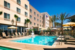 a pool in front of a hotel with chairs and umbrellas at Fairfield Inn & Suites by Marriott Tustin Orange County in Tustin