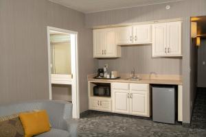 a kitchen with white cabinets and a sink and a couch at Courtyard by Marriott Erie Ambassador Conference Center in Erie