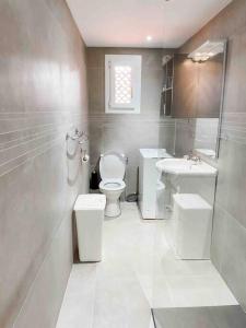 a white bathroom with two toilets and a sink at SanCiprianu à 5minutes de la plage in Lecci