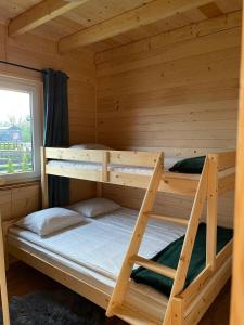Etagenbett in einem Blockhaus mit Fenster in der Unterkunft Bella Przystań in Zator