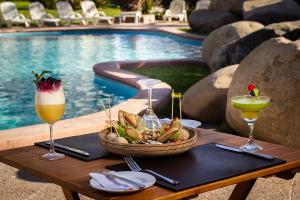 a table with drinks and a basket of food next to a pool at Hotel Club La Serena in La Serena