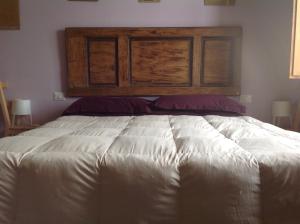 1 cama con cabecero de madera en un dormitorio en Il Glicine 3, en San Gimignano