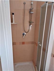 baño con ducha y puerta de cristal en Appartamento Calarossa Sardegna CasaRosa, en Isola Rossa
