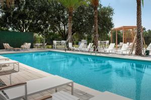 uma piscina com espreguiçadeiras brancas e palmeiras em Element Orlando Universal Blvd. em Orlando