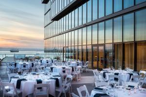 un restaurante con mesas y sillas blancas y un edificio en SpringHill Suites by Marriott San Diego Downtown/Bayfront, en San Diego