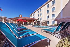 a row of blue lounge chairs next to a building at TownePlace Suites by Marriott Odessa in Odessa