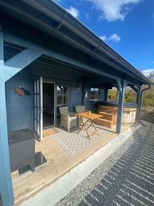 a blue house with a wooden deck with a table at Highland cabin - relaxing hot tub in Inverness