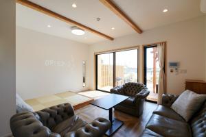 sala de estar con sofás de cuero y mesa en Rush Awaji - Seaside Holiday Home - Self Check-In Only en Awaji