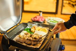 Eine Person kocht Essen auf einem Grill in der Unterkunft Rush Awaji - Seaside Holiday Home - Self Check-In Only in Awaji