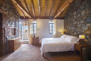 sypialnia z łóżkiem i kamienną ścianą w obiekcie Lyhnos w mieście Askas