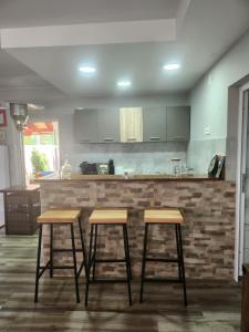 a kitchen with three bar stools in front of a counter at Koreni Celarevo in Čelarevo +16 photos