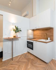 uma cozinha com armários brancos, um lavatório e uma mesa em Charming studio - in the downtown em Budapeste