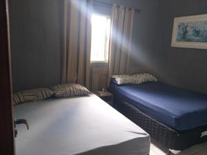 a bedroom with two beds and a window at Cantinho do Rafa in São Lourenço