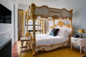 a bedroom with a gold canopy bed and a chair at The Serangoon House, Singapore, a Tribute Portfolio Hotel in Singapore