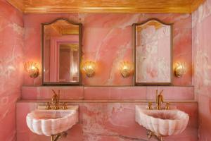 dois lavatórios numa casa de banho cor-de-rosa com dois espelhos em The Serangoon House, Singapore, a Tribute Portfolio Hotel em Singapura