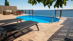 een zwembad met een tafel en stoelen en de oceaan bij Zante Xigia Bay villas in Khartáta