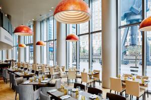 un restaurante con mesas, sillas y ventanas grandes en Marriott Executive Apartments London, Canary Wharf, en Londres