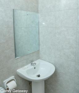 a bathroom with a white sink and a mirror at Comfy Getaway STUDIO apartment near JKIA & SGR with KING BED, WIFI, NETFLIX and SECURE PARKING in Syokimau